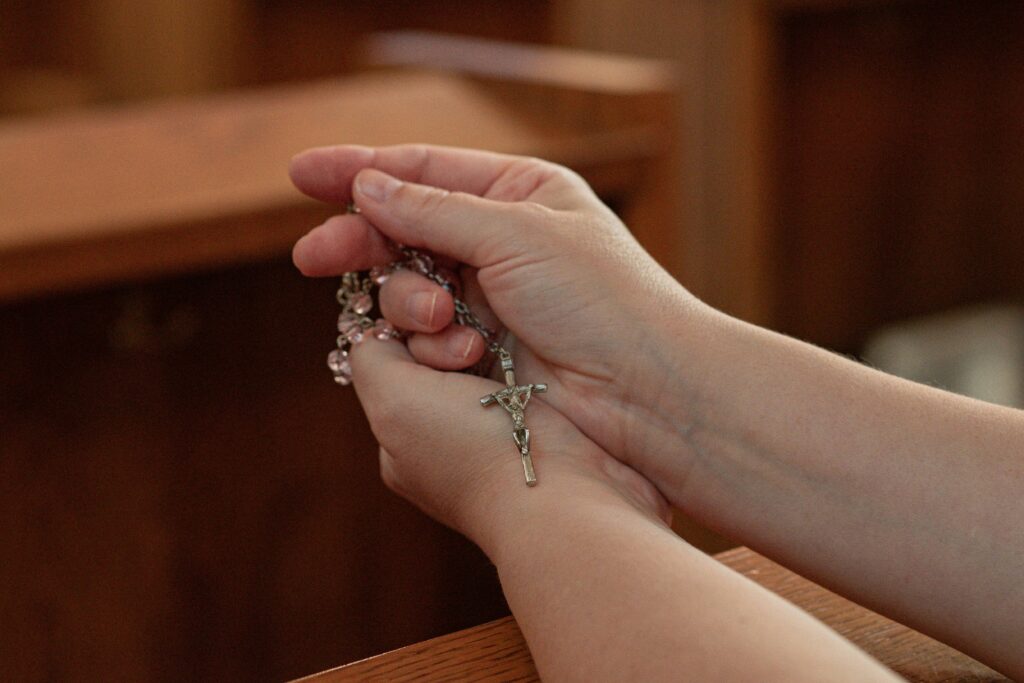 Hands gently holding a rosary in prayer, symbolizing the integration of grace, faith, and emotional healing.